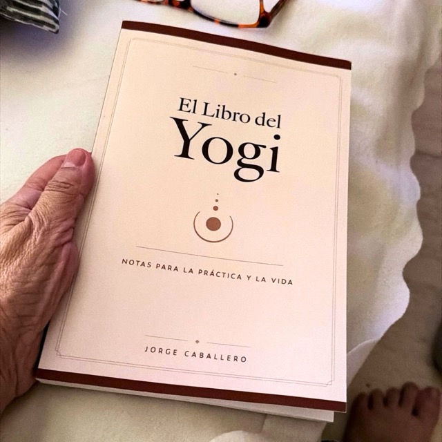 El libro del Yogi sujetado en la mano, junto a unas gafas